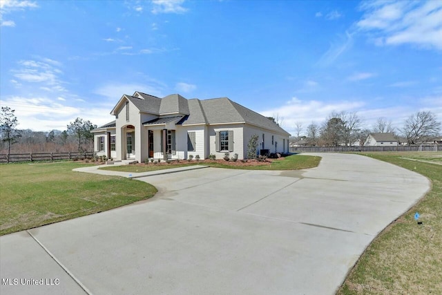 view of front of property with concrete driveway, fence, a front lawn, and a standing seam roof