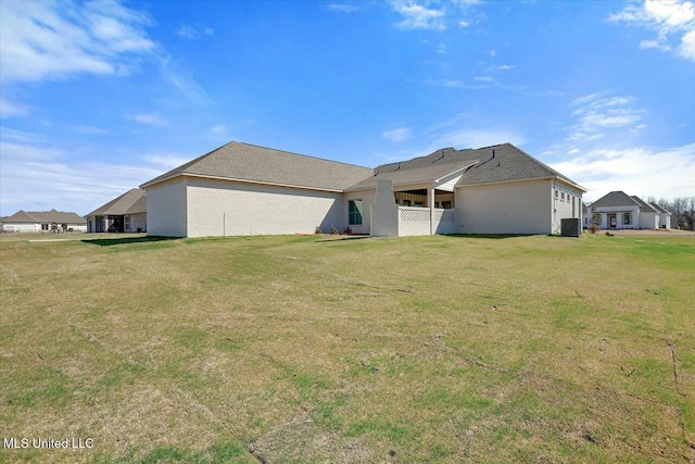 rear view of house with central AC and a yard