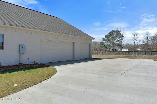 view of home's exterior featuring a shingled roof, fence, and a garage