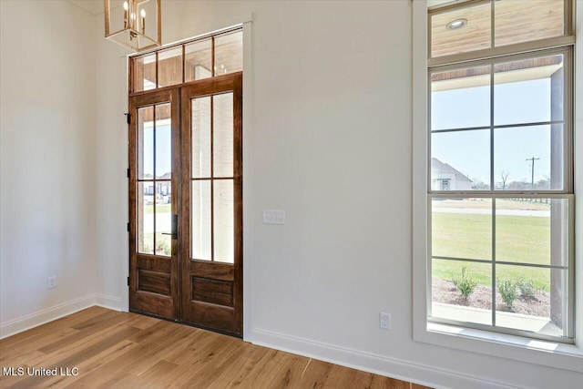 entryway with a notable chandelier, french doors, wood finished floors, and baseboards