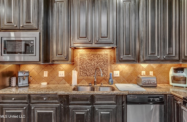 kitchen featuring light stone counters, appliances with stainless steel finishes, sink, and dark brown cabinets