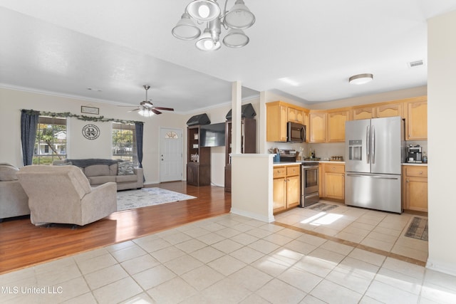 kitchen featuring light tile patterned floors, stainless steel appliances, ceiling fan with notable chandelier, and ornamental molding