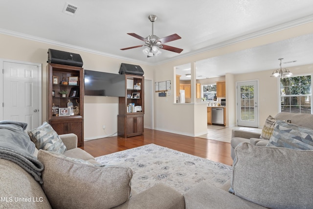 living room with ceiling fan with notable chandelier, light hardwood / wood-style floors, and ornamental molding