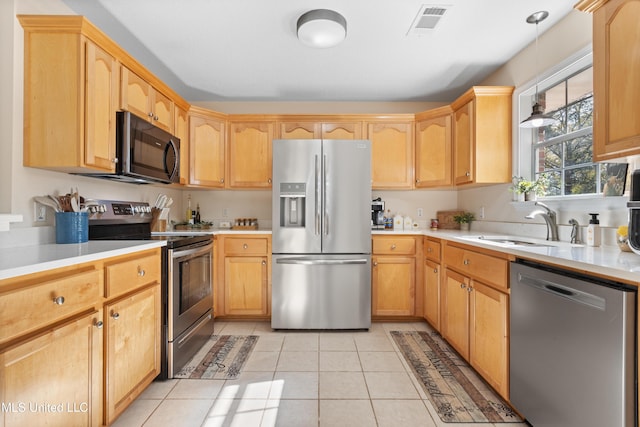 kitchen with pendant lighting, light brown cabinets, sink, light tile patterned floors, and stainless steel appliances