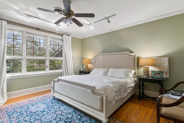 bedroom with multiple windows, track lighting, wood-type flooring, and ceiling fan