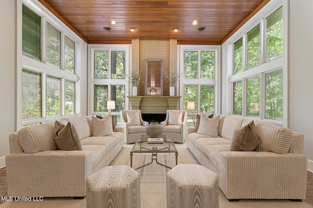 sunroom featuring wood ceiling, a fireplace, and a wealth of natural light