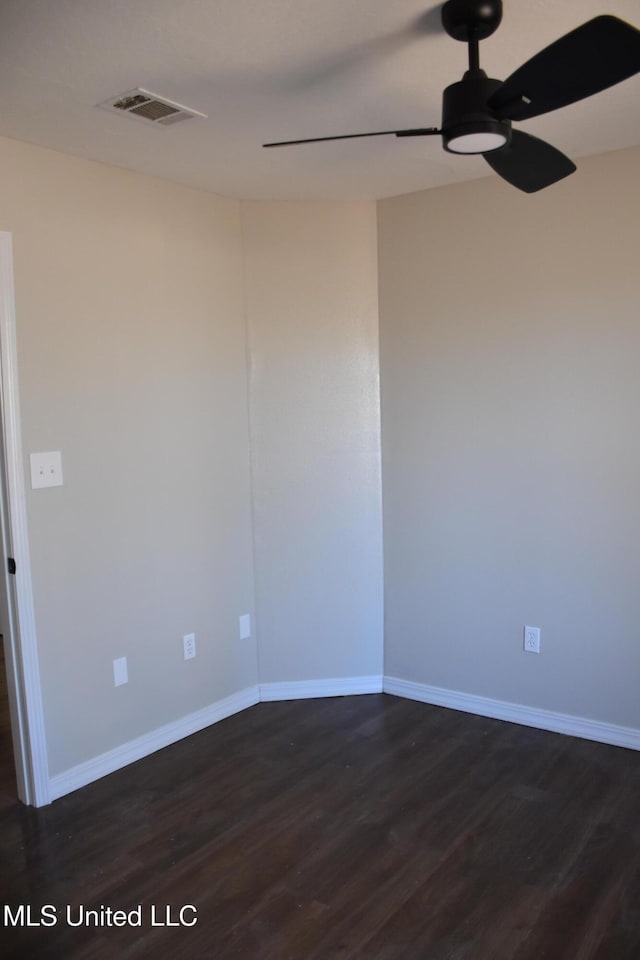 empty room with baseboards, dark wood-style floors, visible vents, and ceiling fan