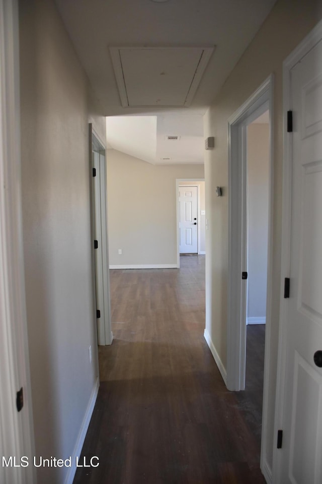 corridor featuring attic access, baseboards, and wood finished floors