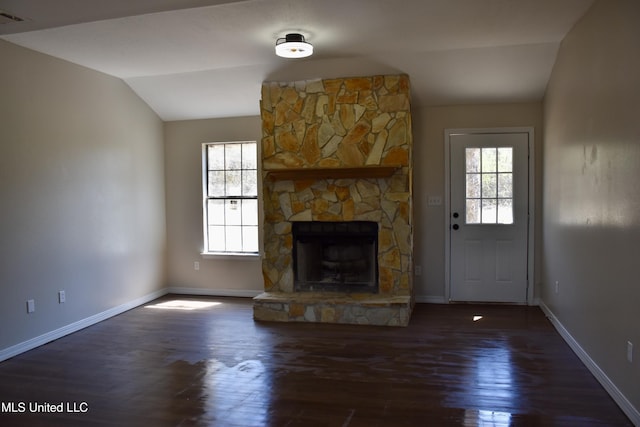 unfurnished living room featuring a healthy amount of sunlight, wood finished floors, a fireplace, and vaulted ceiling