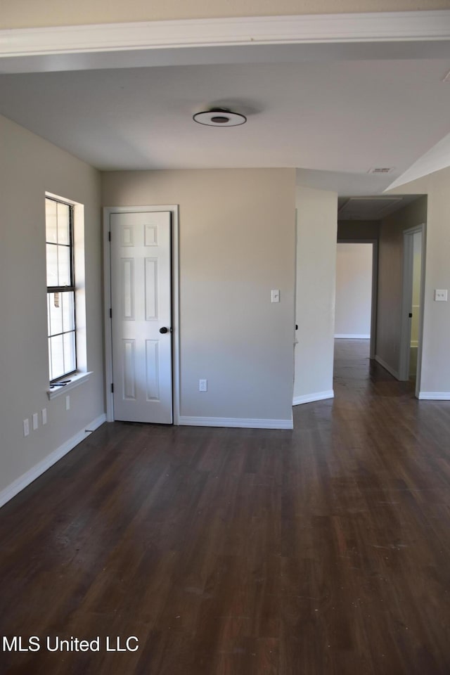 spare room featuring visible vents, baseboards, and dark wood-style flooring