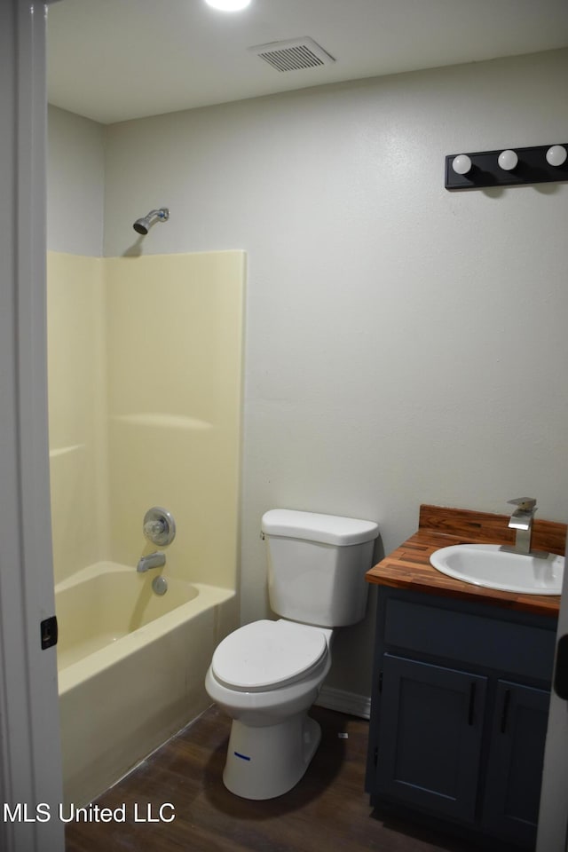 bathroom featuring visible vents, toilet, vanity, wood finished floors, and washtub / shower combination