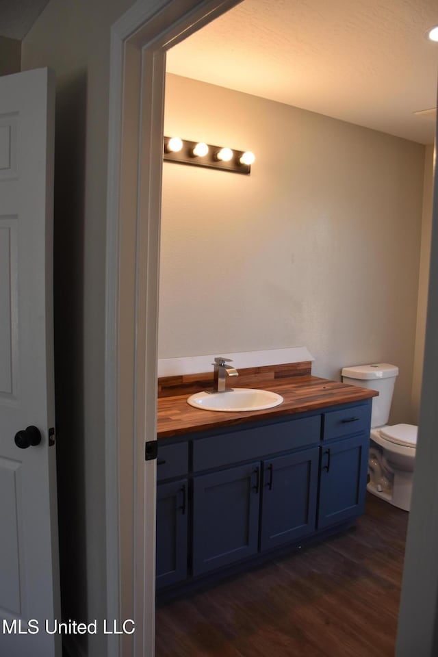 bathroom featuring toilet, wood finished floors, and vanity