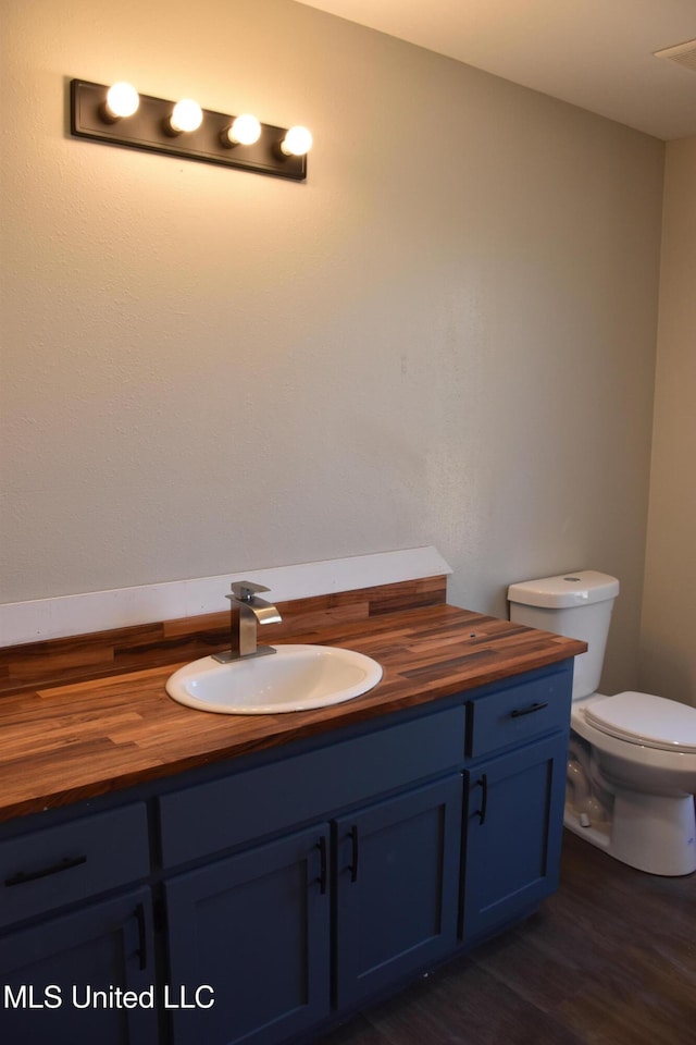 bathroom featuring vanity, toilet, and wood finished floors