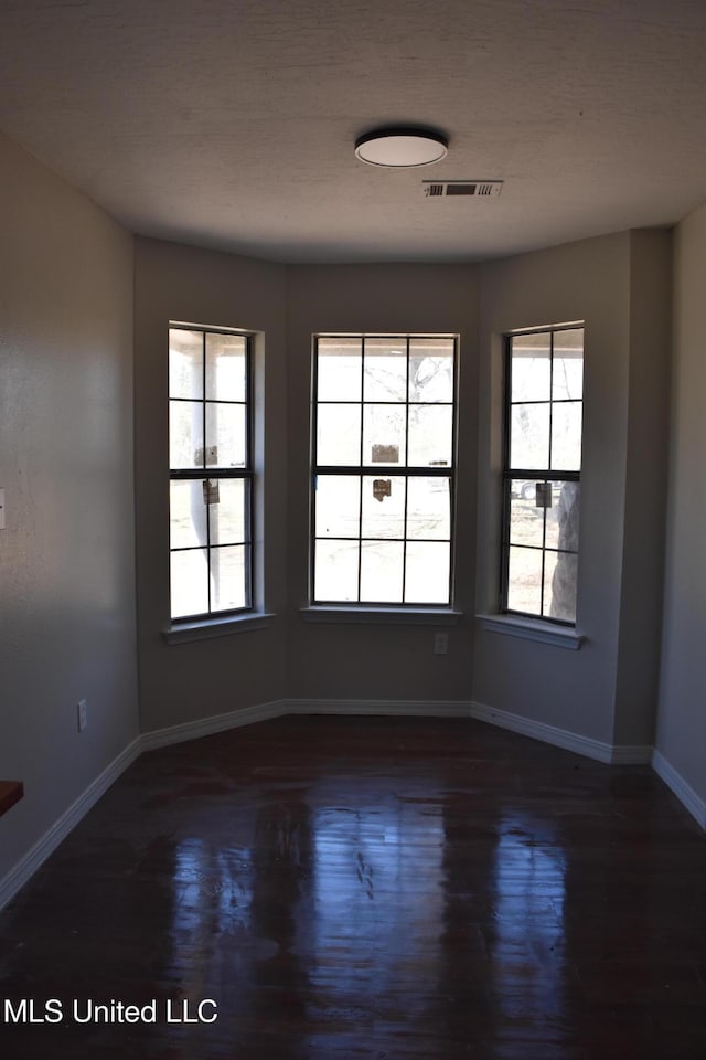 empty room featuring visible vents, baseboards, and wood finished floors