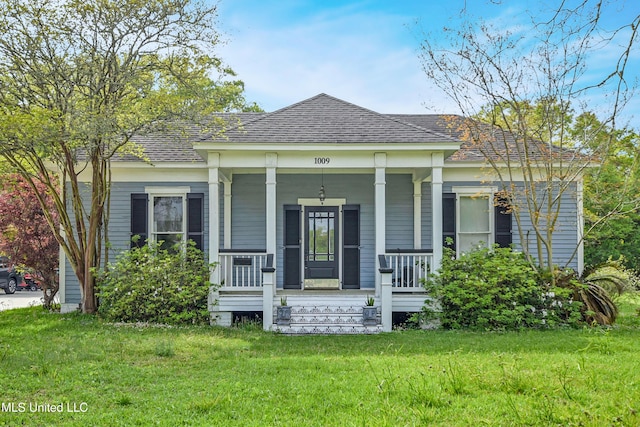 view of front facade featuring a porch, a front yard, and roof with shingles