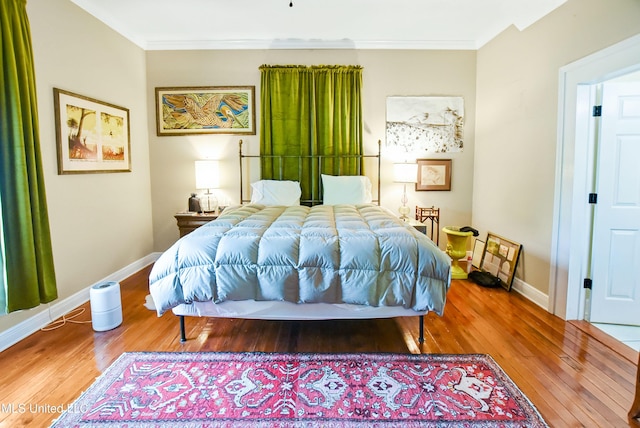 bedroom with baseboards, ornamental molding, and wood-type flooring