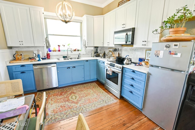 kitchen with light countertops, crown molding, blue cabinetry, stainless steel appliances, and a sink