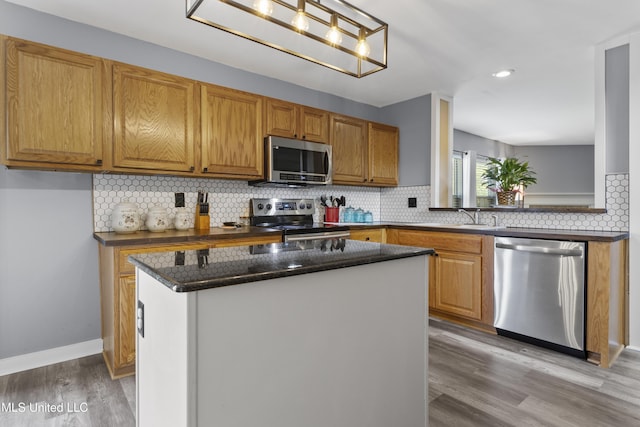 11222 Cypress Bayou Dr, Gulfport, MS 39503 - kitchen featuring dark stone countertops, tasteful backsplash, light wood-style flooring, appliances with stainless steel finishes, and a kitchen island