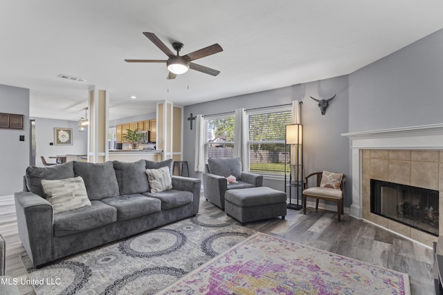 11222 Cypress Bayou Dr, Gulfport, MS 39503 - living room featuring a fireplace, a ceiling fan, visible vents, baseboards, and wood finished floors