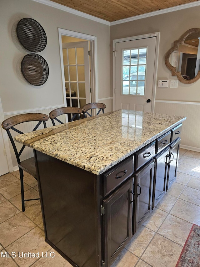 447 Shaker Dr, Senatobia, MS 38668 - kitchen featuring a wainscoted wall, light stone counters, a kitchen breakfast bar, a center island, and crown molding
