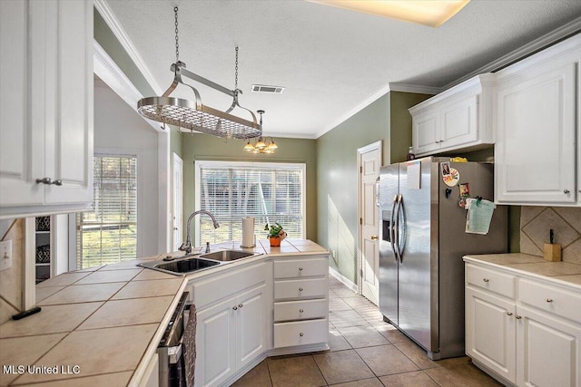 kitchen featuring tile counters, white cabinets, decorative light fixtures, and sink