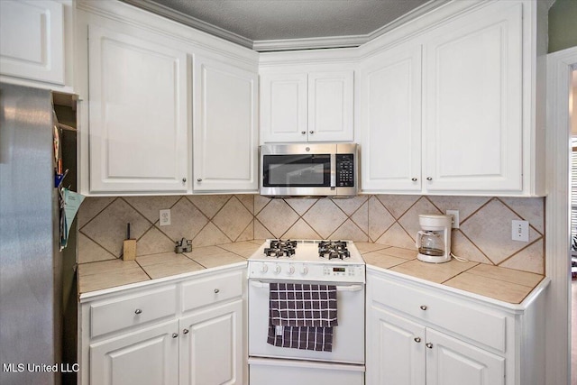 kitchen featuring white cabinets, backsplash, stainless steel appliances, and tile countertops