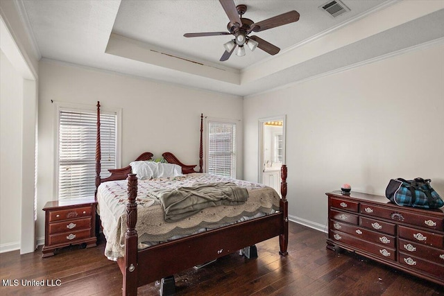 bedroom with dark hardwood / wood-style floors, a tray ceiling, ceiling fan, and ensuite bathroom