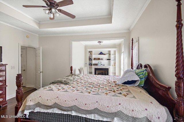 bedroom featuring ceiling fan, dark hardwood / wood-style floors, crown molding, and a tray ceiling