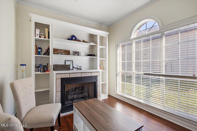 living room with crown molding, dark wood-type flooring, and a tile fireplace