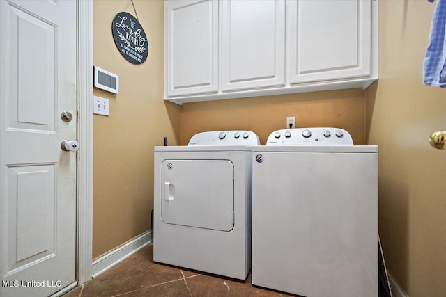 laundry room with cabinets, washing machine and dryer, and dark tile patterned floors