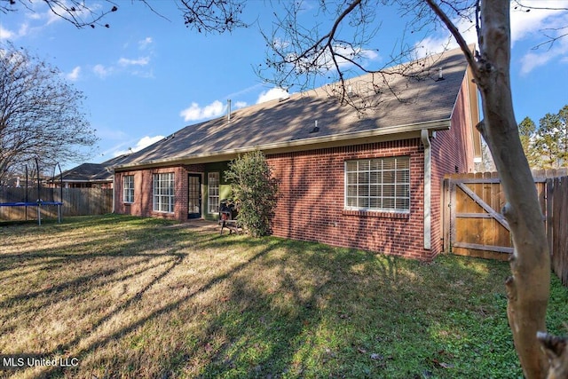 rear view of house featuring a yard and a trampoline