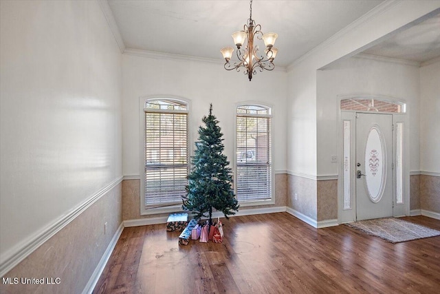 foyer with wood-type flooring, a notable chandelier, and ornamental molding