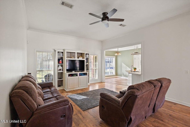 living room featuring ceiling fan, a healthy amount of sunlight, wood-type flooring, and crown molding