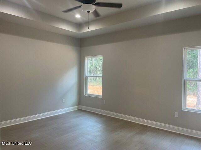 empty room featuring ceiling fan, a healthy amount of sunlight, and dark hardwood / wood-style floors