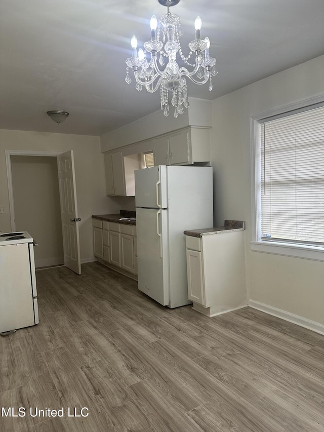 kitchen featuring an inviting chandelier, white appliances, wood finished floors, and baseboards