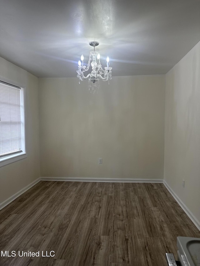 unfurnished dining area with dark wood-style floors, baseboards, and a chandelier