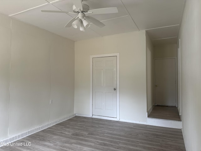 empty room with baseboards, a ceiling fan, and wood finished floors