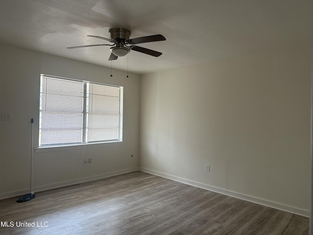 spare room featuring a textured ceiling, wood finished floors, baseboards, and ceiling fan