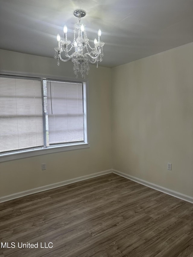 unfurnished room featuring baseboards, an inviting chandelier, and dark wood-style floors