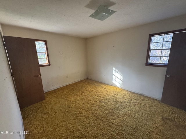 carpeted spare room featuring a textured ceiling