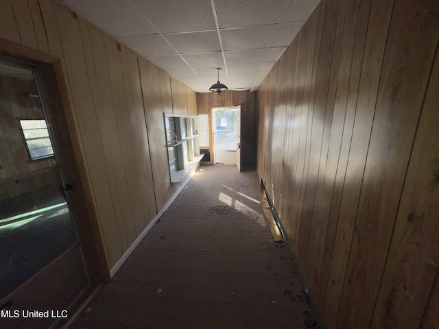 corridor featuring a drop ceiling and wood walls