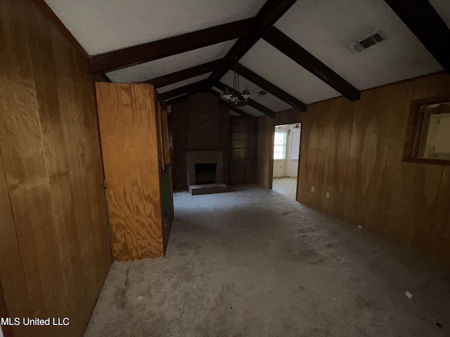 unfurnished living room featuring lofted ceiling with beams, light carpet, wooden walls, and a brick fireplace