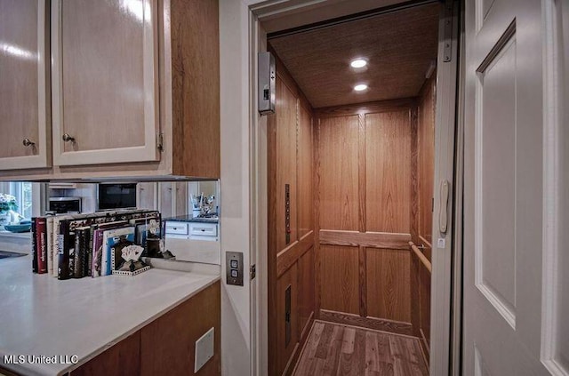 details featuring hardwood / wood-style flooring, wooden walls, and elevator