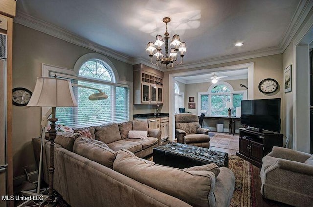 living room with crown molding, ceiling fan with notable chandelier, and a healthy amount of sunlight