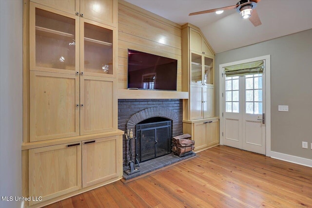 unfurnished living room with lofted ceiling, light hardwood / wood-style flooring, a brick fireplace, and ceiling fan