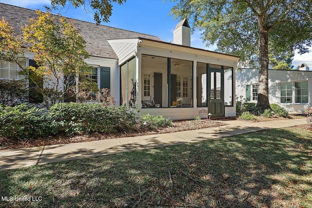 back of property featuring a sunroom and a lawn