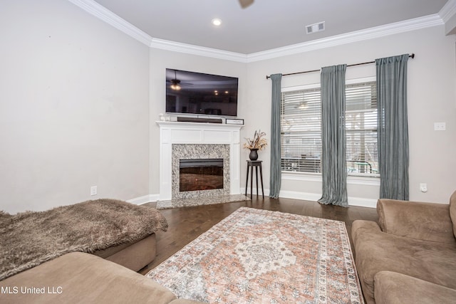 living room featuring dark hardwood / wood-style flooring, crown molding, a premium fireplace, and ceiling fan