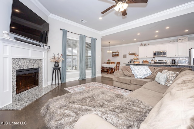 living room featuring crown molding, ceiling fan, a fireplace, and dark hardwood / wood-style floors