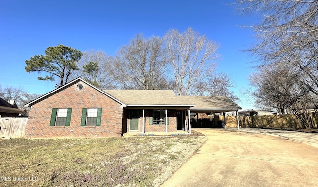 ranch-style home featuring a front lawn, driveway, fence, a carport, and brick siding