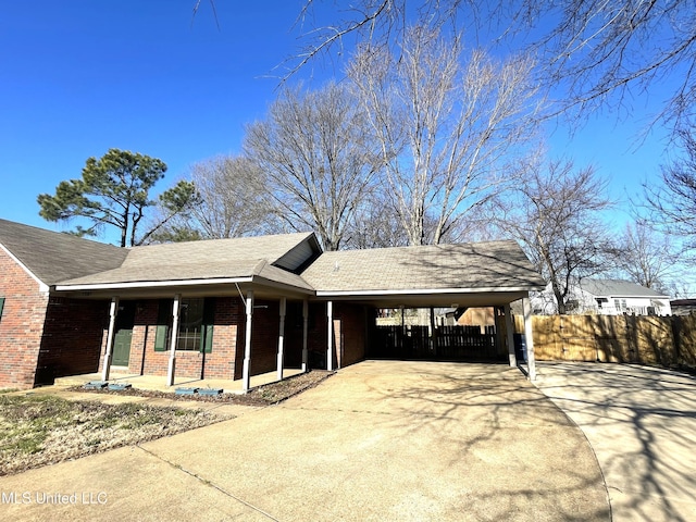 view of front of home featuring concrete driveway, covered porch, fence, and brick siding